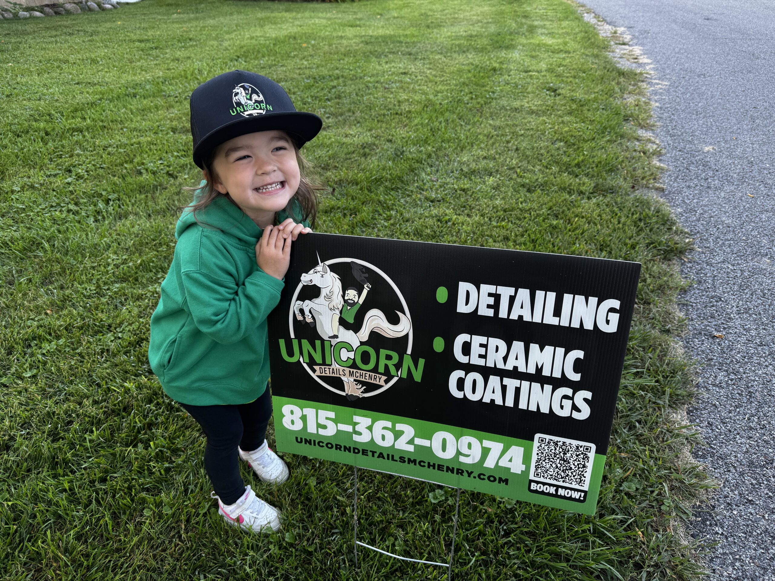 Kora, official spokesperson of Unicorn Details McHenry, posing with a yard sign